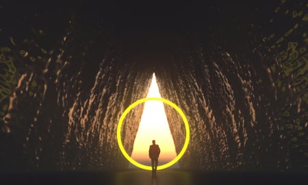 The silhouette of a man looking out of the triangular entrance to a cave while surrounded by a glowing ring of light.
