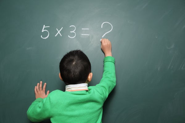 Young boy writes a math equation on a chalkboard, but unable to solve, "5x3=?"