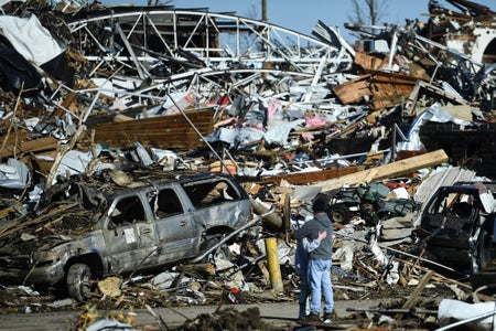People embrace while viewing tornado damage in Mayfield, Kentucky.