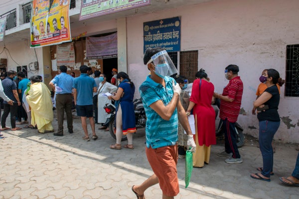 A man holds his arm after getting COVID vaccine while walking across a sunny street in the Indian state of Uttar Pradesh.