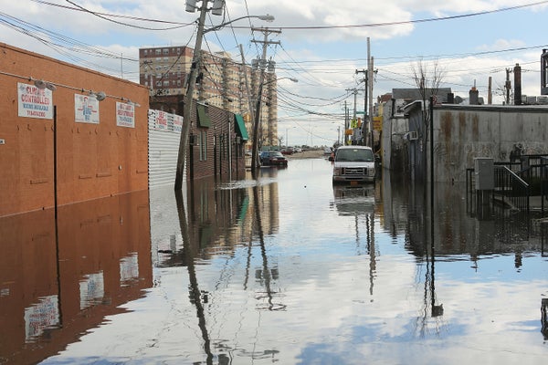 Flood waters from Superstorm Sandy in 2012 reach into the wheel wells of cars parked on an industrial street in New York City.