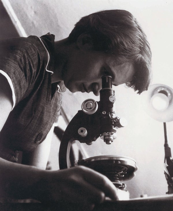 Rosalind Franklin looking into a microscope.