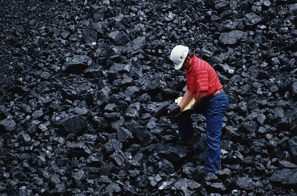 man standing on pile of coal