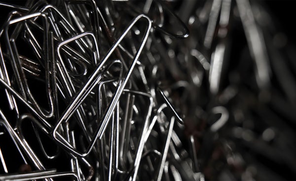 closeup macro shot of a large pile of triangular shaped shiny silver paper clips on black