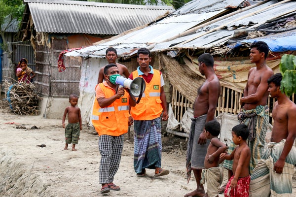 Residents stand outside homes as volunteers warn of cyclone