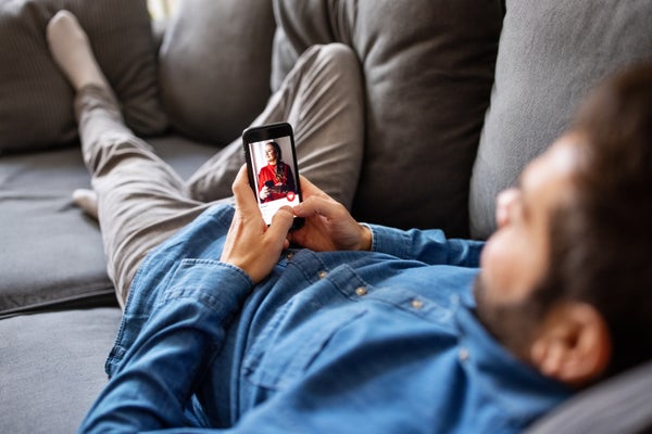 Man laying on couch using dating app.
