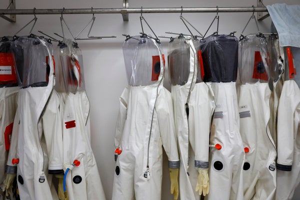 White, full-body-coverage biosafety suits hang on the rack at a training lab in Montana.