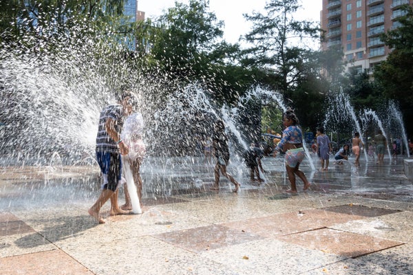 Children play in a fountain in a downtown area.