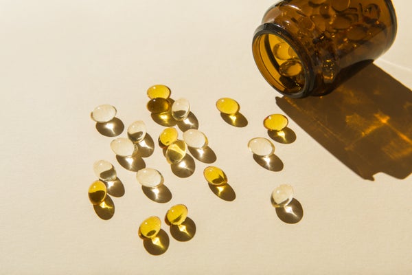 Vitamin D capsules poured out of the bottle on a beige background