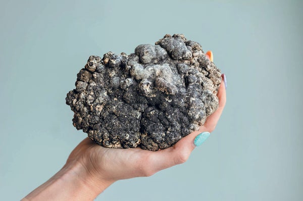 A polymetallic nodule held in a peron's hand.