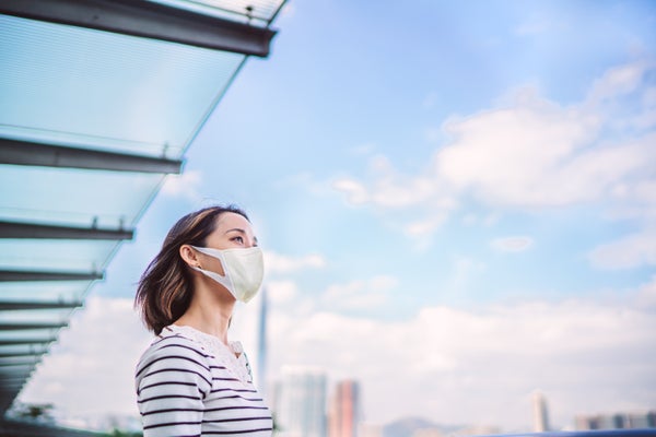 Young woman wearing face mask looking out over city.