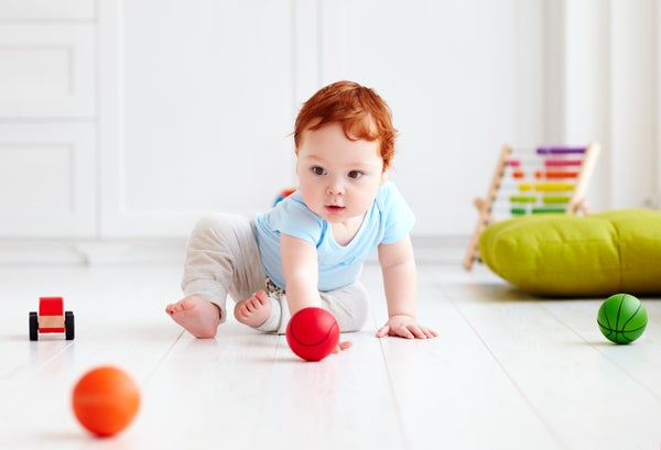 Cute baby on the floor at home playing with colorful balls