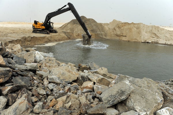 A construction vehicle scoops sand from an open pit
