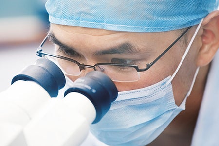 doctor looking through microscope
