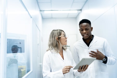 Colleagues using digital tablet in laboratory