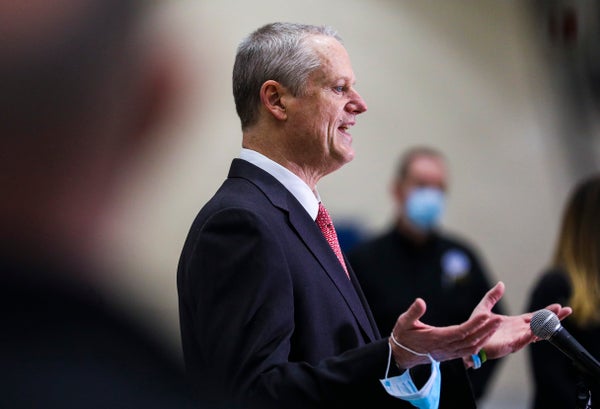 Charlie Baker speaking while holding a mask.
