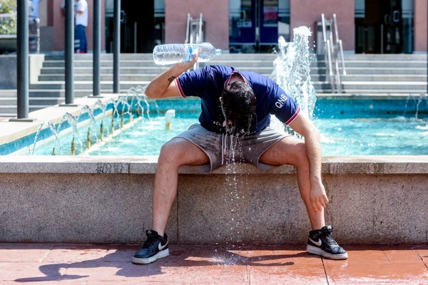 A young man throws a bottle of water over himself to combat the second heat wave of the summer, on 12 July, 2022 in Madrid, Spain.