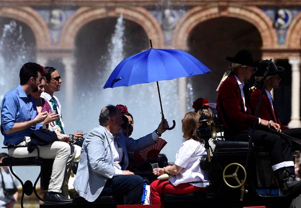 A group of people on a horse-drawn carriage and a blue umbrella.