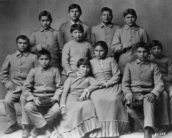 1886 group portrait of Chiracahua Apache children wearing mandated school uniforms.