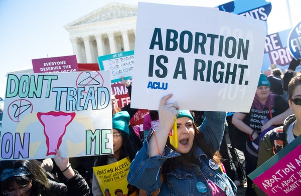 People hold signs about abortion rights and shout.