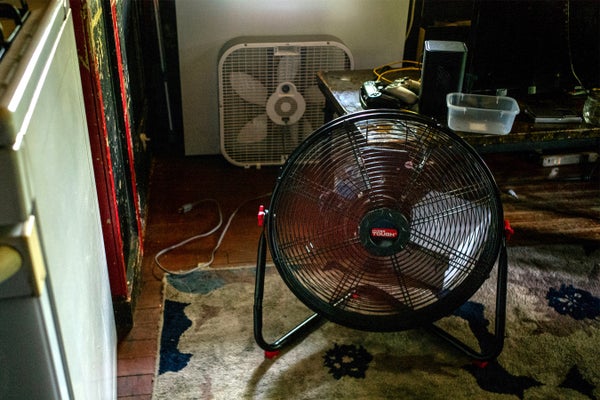 Two fans on a floor next to a stove in an apartment in Houston during a heatwave.