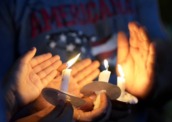 Hands hold candles at an evening vigil.