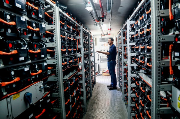 Man standing between rows of Lithium Ion batteries in storage center.