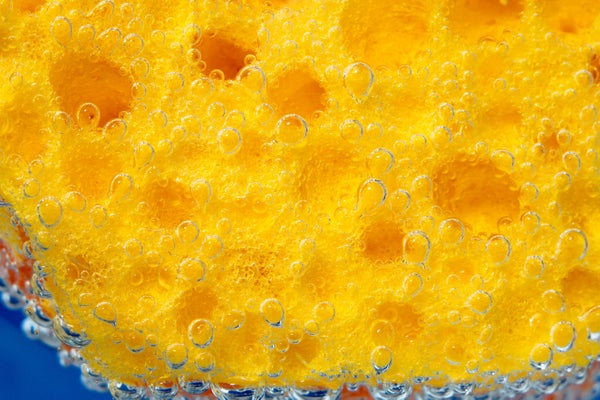 A yellow sponge underwater with air bubbles.