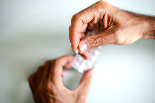 A man's hand holding a pill.