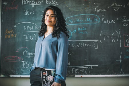 Astrophysicist Ekta Patel standing in front of a board.