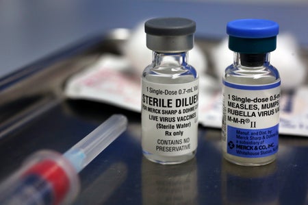 A vial containing the MMR vaccine, right, and another vial containing the diluent used to mix the vaccine, sit on a tray before being loaded into a syringe