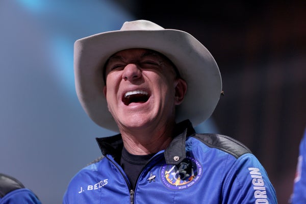 A laughing man in a blue jacket and a cowboy hat.