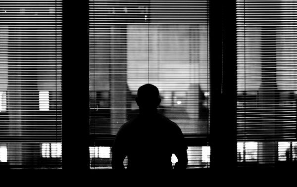 Silhouette of a man looking through an office window