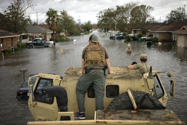A resuce team searches a flooded neighborhood from a high water vehicle.