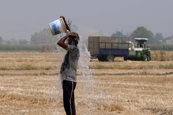 A man in a field dumps a bucket of water on his head