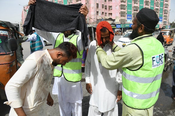 Men assist each other with towels to keep cool