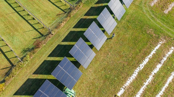 Overhead shot of woman walking near solar panels on farm