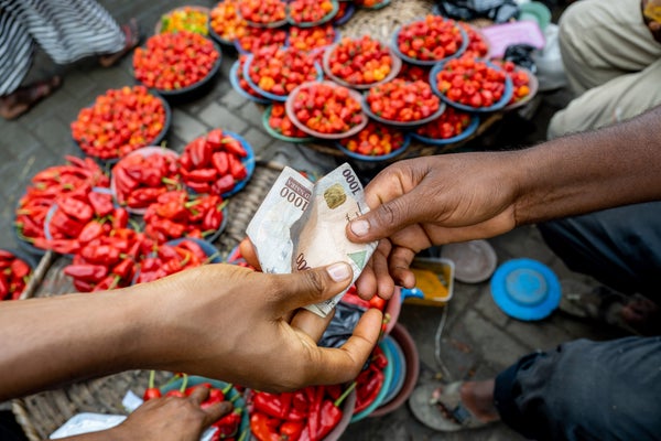 A customer hands a vendor a 1000 Nigerian naira banknote at the Mile 12 food market in Lagos, Nigeria.