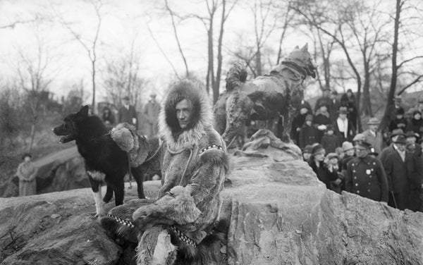 Archival image of musher with his husky dog, with statue of dog in background