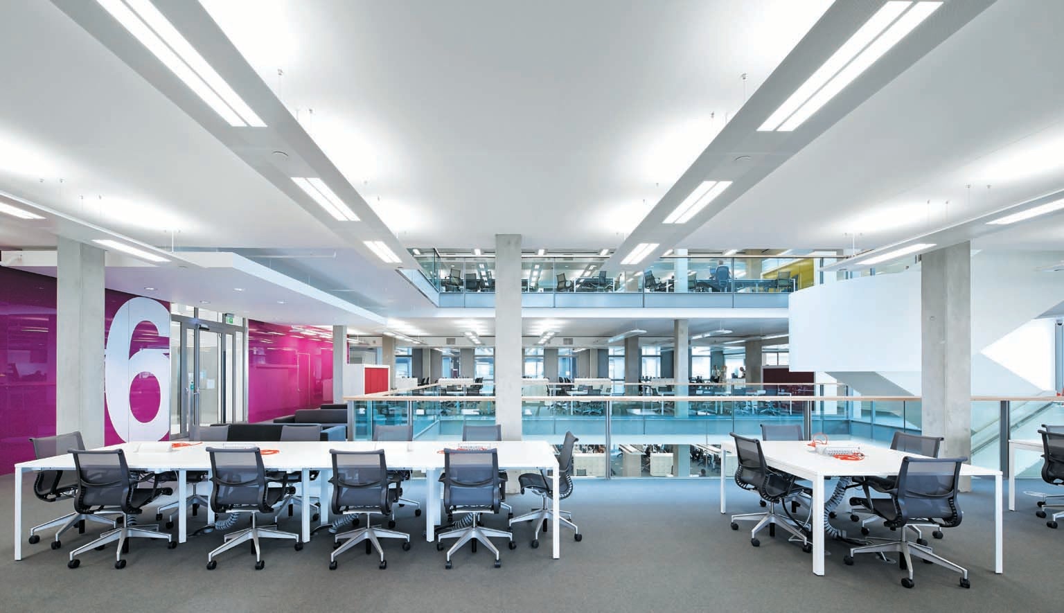Interior view of open office plan space with harsh florescent lighting and shared seating area.