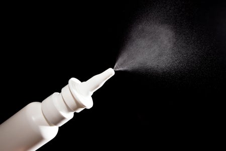 Nasal drug spray against black background.