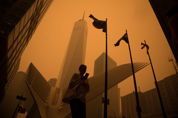 A pedestrian silhouetted against orange, smoke-filled city skyline