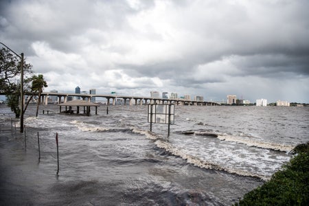 Storm surge flood waters swirl under cloudy skies.