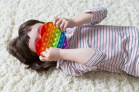 Young little girl playing with popular pop-it kids toy.