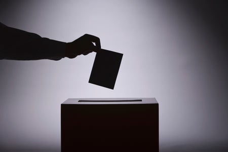 B/w Silhouette of person putting ballot in box