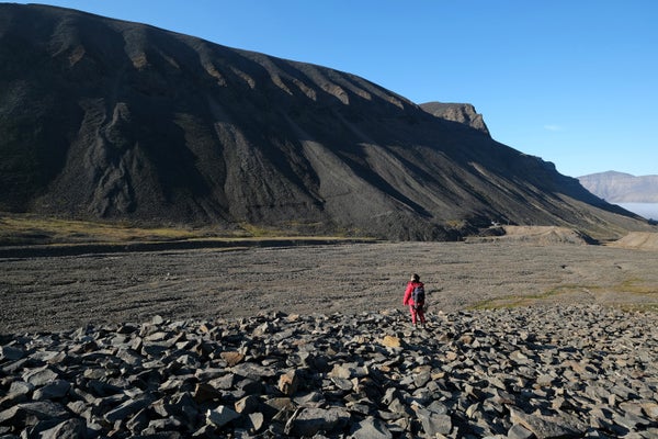 A hiker stands in a valley once filled by the nearby melting Longyearbreen glacier during a summer heat wave on Svalbard archipelago on July 31, 2020.