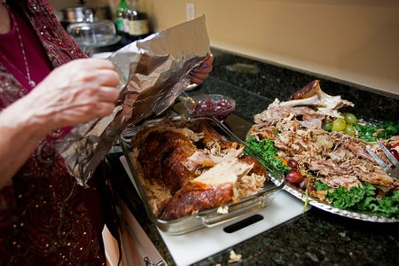 Woman wraps up leftover turkey from Thanksgiving dinner