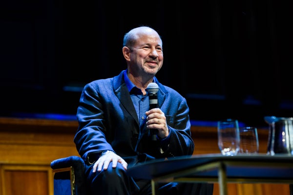 Michael Mann sitting in a blue suit holding a microphone