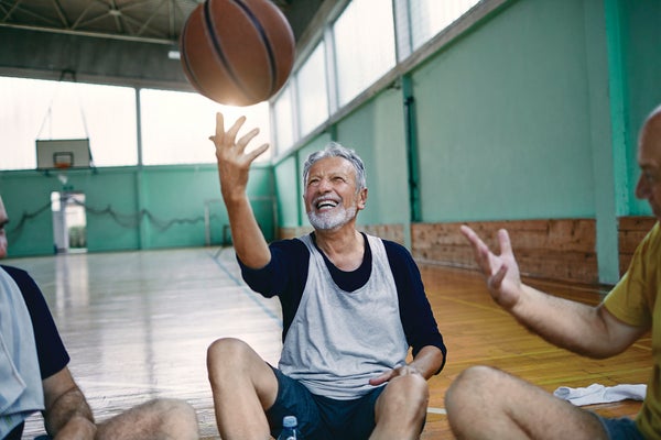 Older man smiling while playing with a basketball.