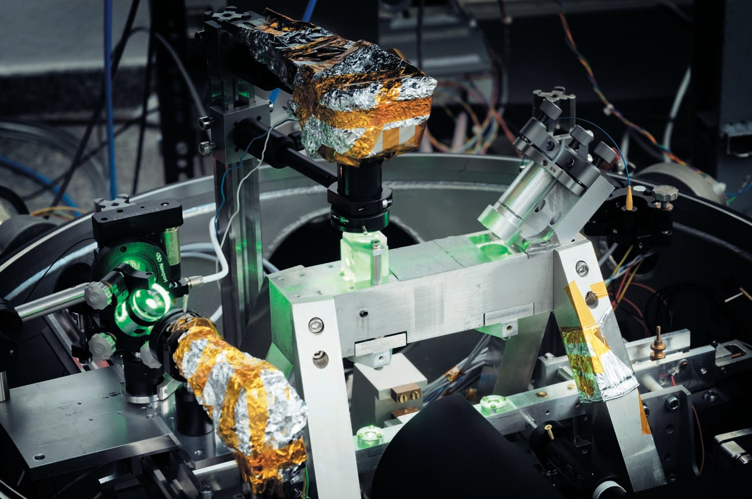 Detail view of metallic scientific equipment illuminated with green laser light.